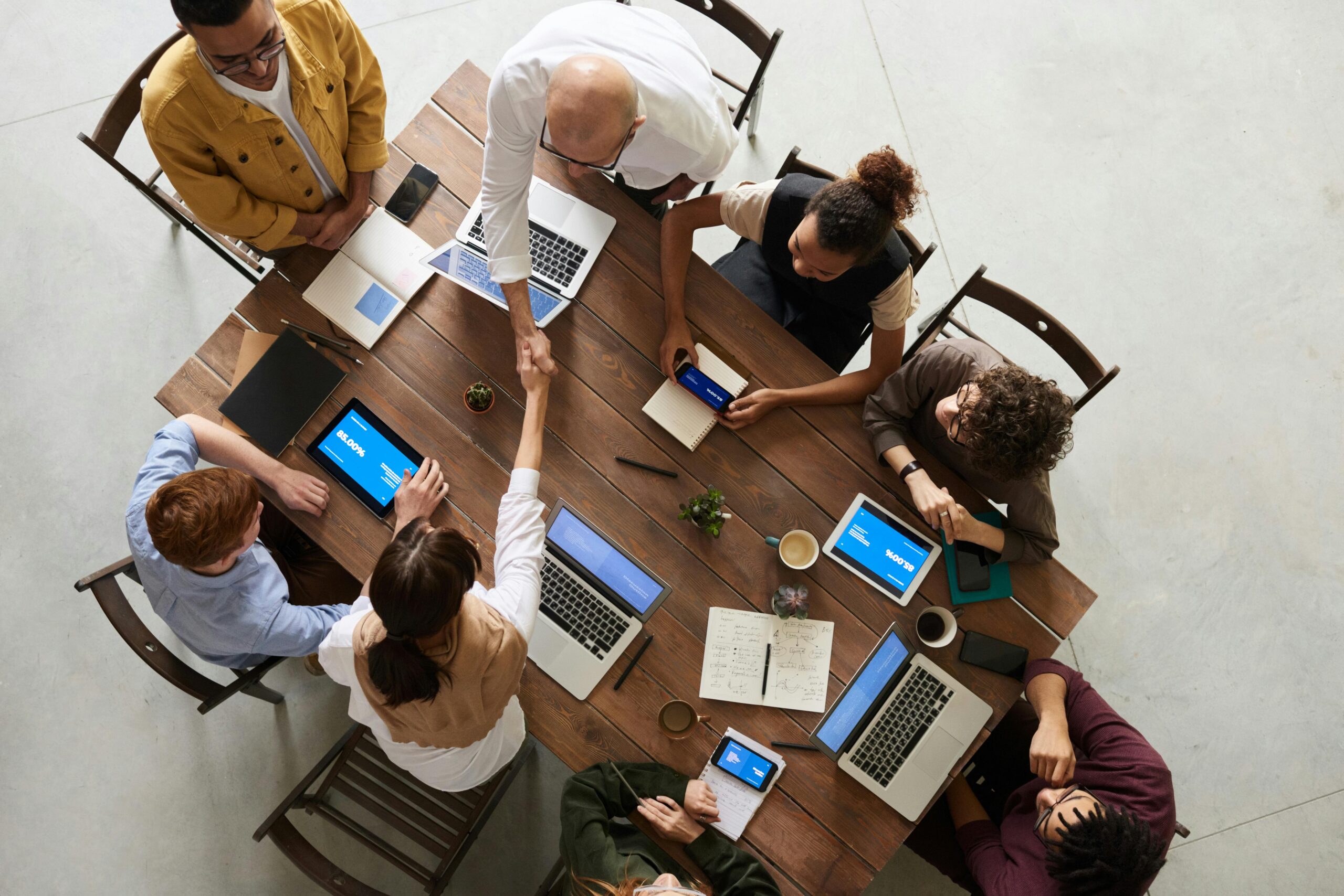 Top view of a diverse team collaborating in an office setting with laptops and tablets, promoting cooperation. team meeting clarity improvement